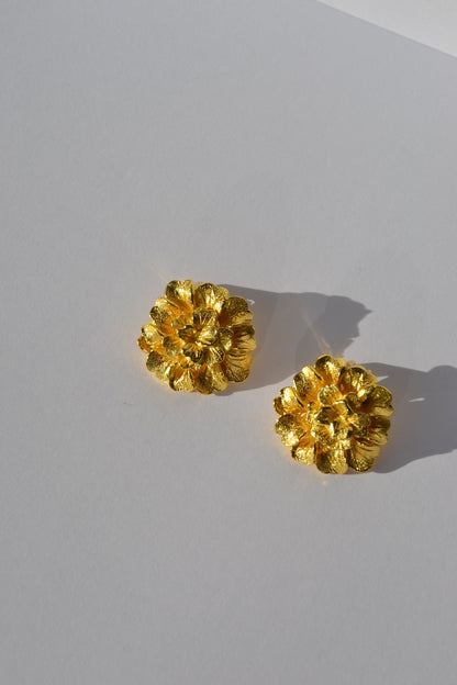 Boucles d'Oreilles Fleurs d'Or - Éclat Doré et Élégance Florale  Embellissez votre look avec nos boucles d'oreilles Fleurs d'Or, une création raffinée et éclatante, faite main par nos artisans. Inspirées par la beauté intemporelle des fleurs, ces boucles d'oreilles capturent l'essence de l'élégance naturelle.  Détails du Design :  Design : Chaque paire présente des motifs floraux délicats et sophistiqués, rehaussés par une finition dorée qui leur confère une allure luxueuse et radieuse.